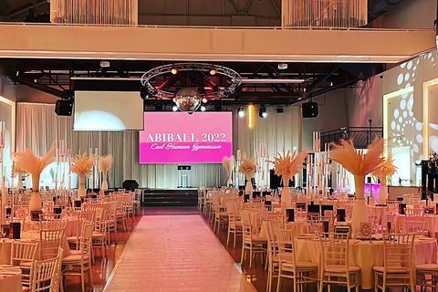 Echtes Foto: Saal zum Abiball 2022 des Carl-Humann-Gymnasiums, runde Tische mit Stuhlreihen, Mittelgang zur Bühne mit Leinwand.