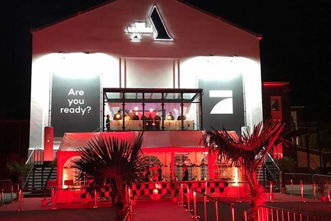 Echtes Foto: The Address bei Nacht zur Aftershow-Party von Germany’s Next Topmodel, rot beleuchteter Eingang mit Palmen, am Giebel das ProSieben-Logo.