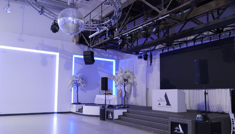 Echtes Foto: Bühne mit Treppe und großer LED-Wand, davor freie Tanzfläche.